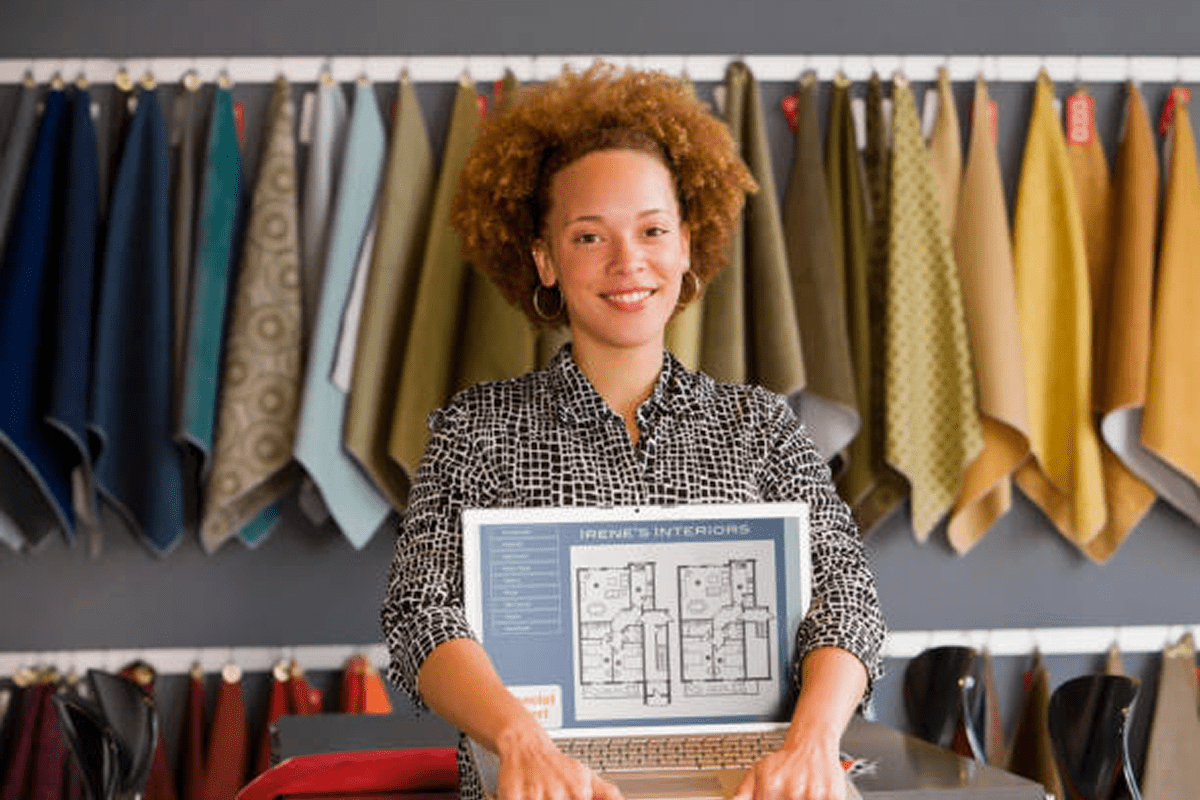 Smiling designer holding a blueprint in a fabric store.
