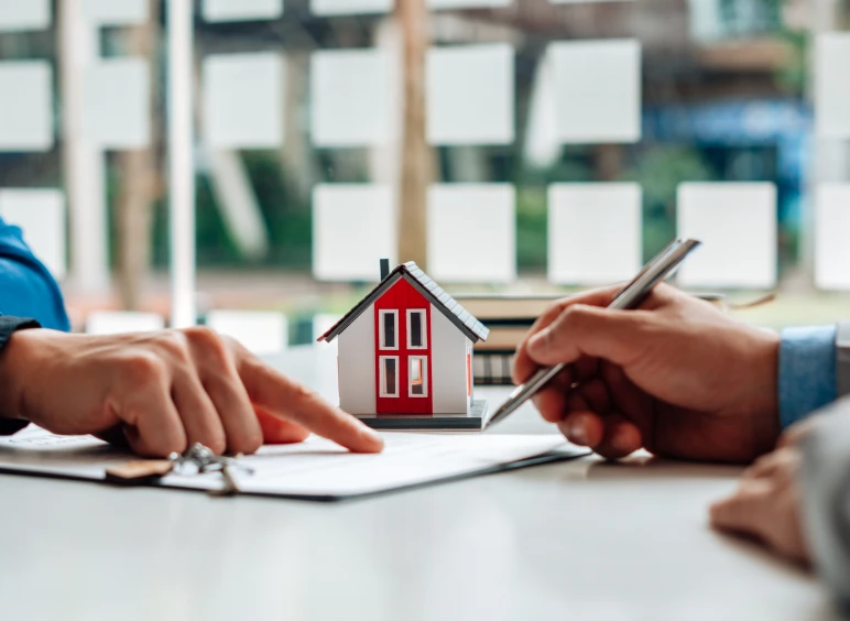 Hands discussing real estate paperwork with model